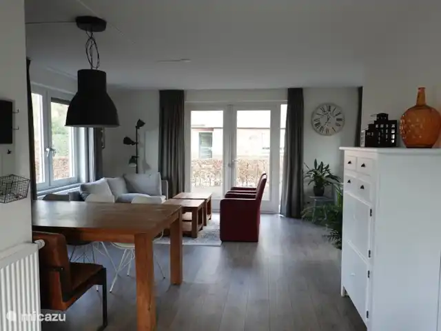 De ruime woonkamer heeft veel ramen en is lekker licht. heeft uitzicht op de tuin die rondom het huisje ligt